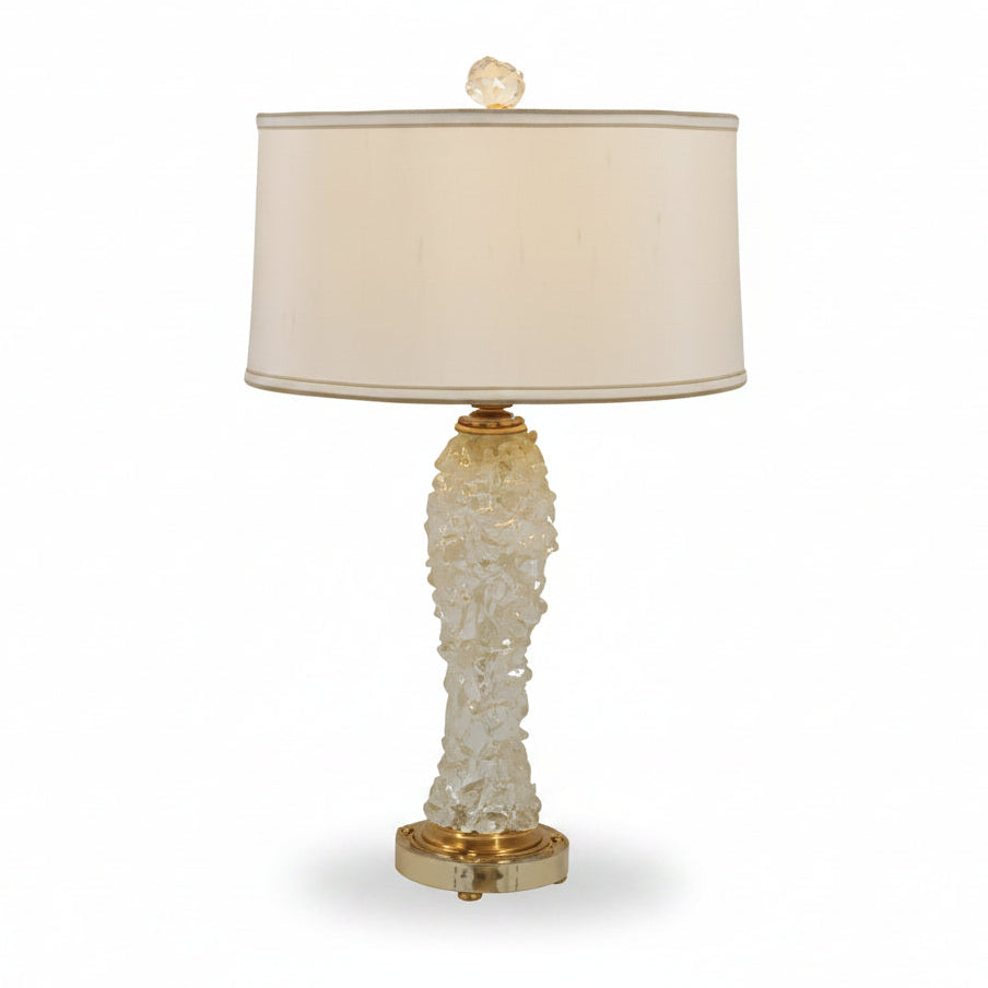 Table lamp with a textured base and beige shade on a white background