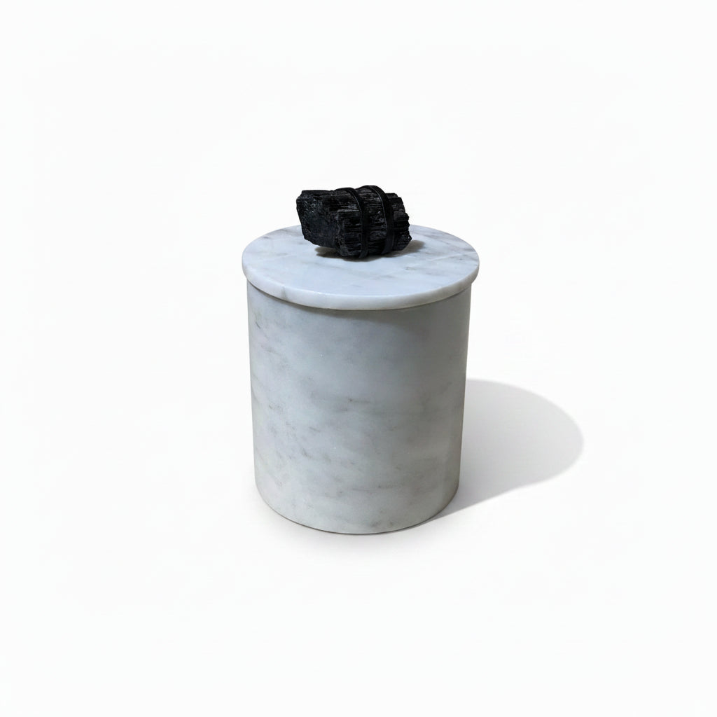 Marble-textured container with a black decorative item on top, placed on a cardboard surface.