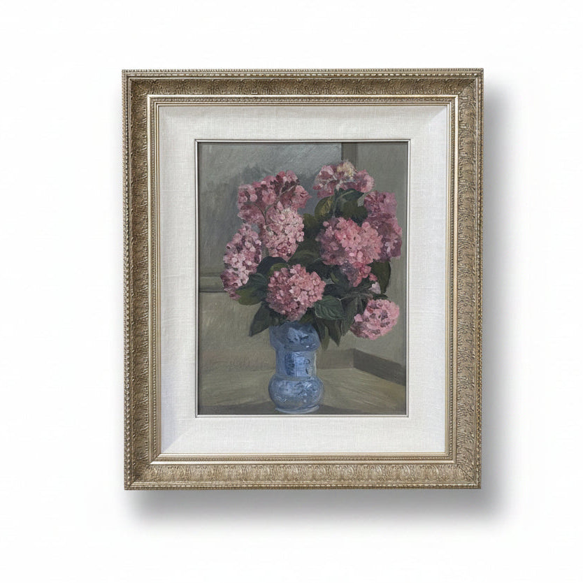 Framed painting of pink flowers in a blue vase on a white wall.