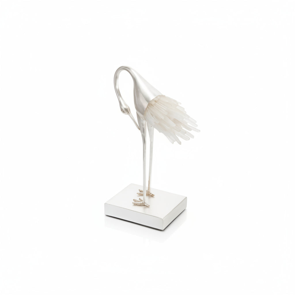 Decorative bird sculpture with crystal feathers on a white base against a white background