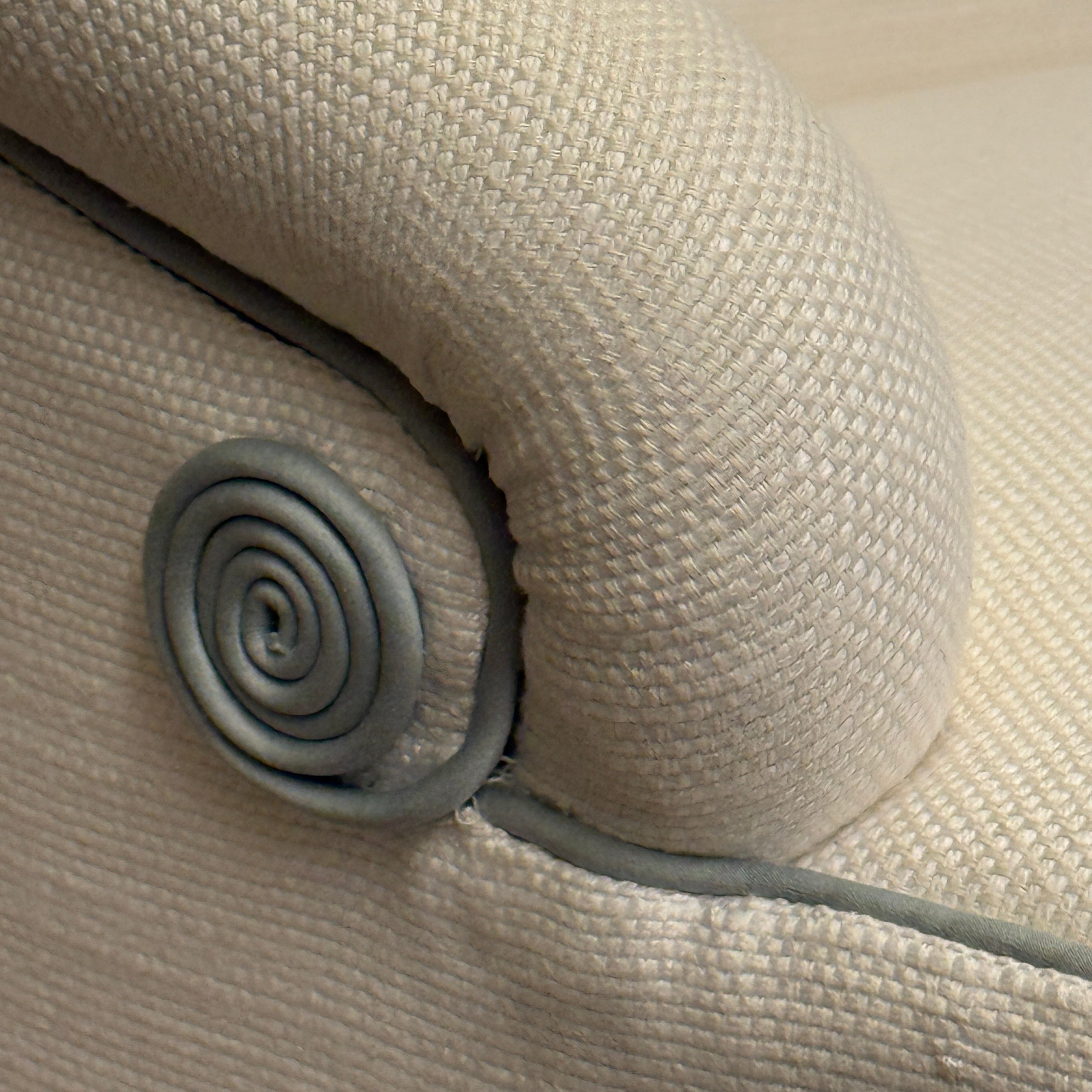 Close-up of a textured beige fabric with a metal coil and wire.