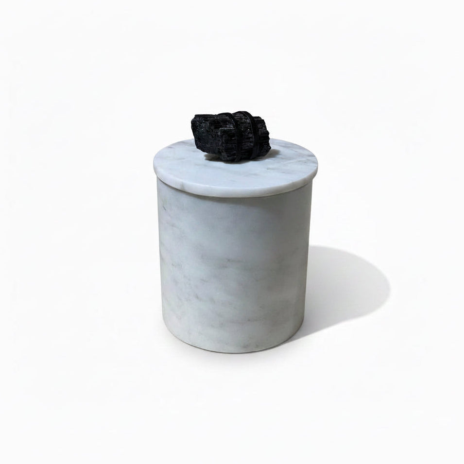 Marble-textured container with a black decorative item on top, placed on a cardboard surface.