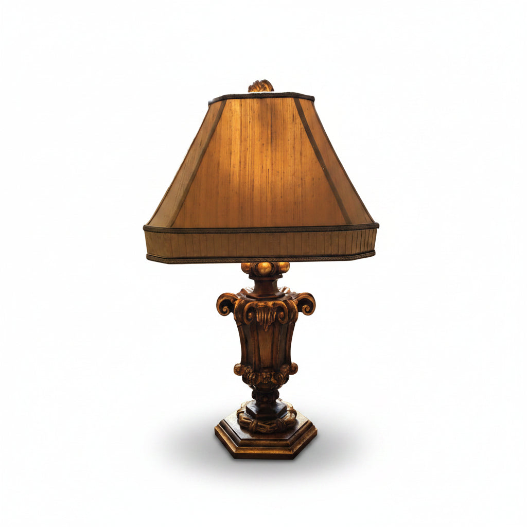 Decorative lamp with a beige shade on a table in front of a window.