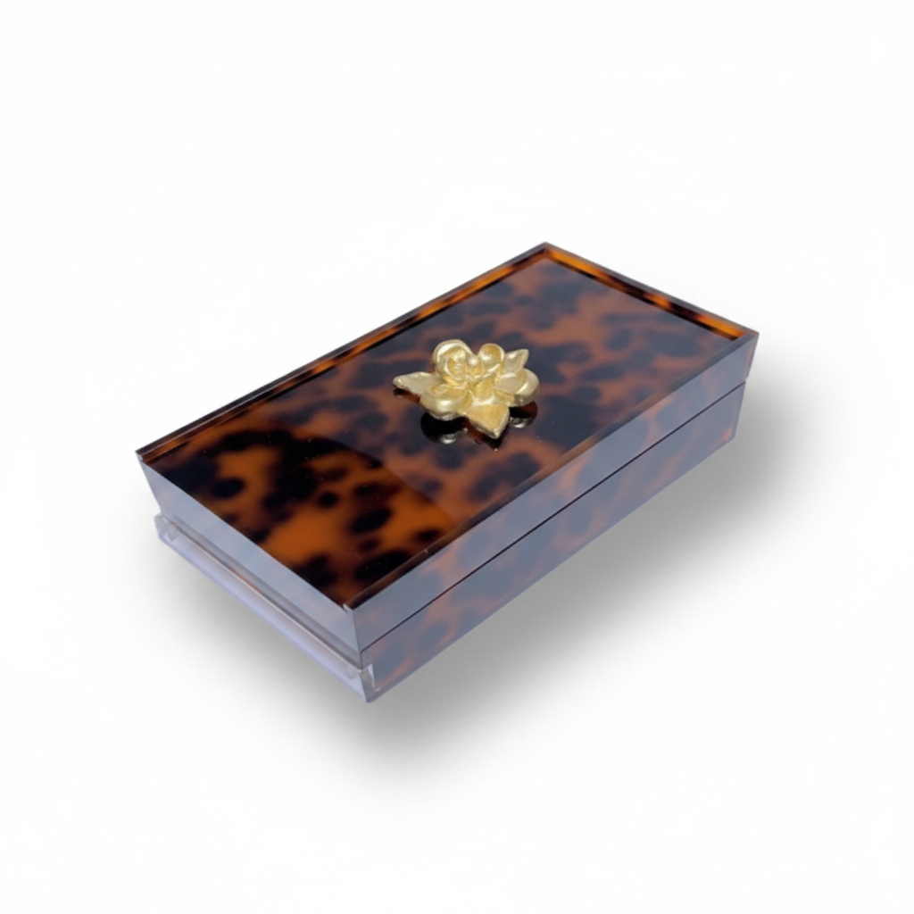 Tortoiseshell-patterned box with a gold flower-shaped knob on a white background